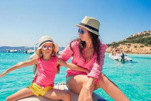 Young mother with her adorable little girls resting on a big boat photo