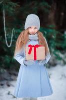 Little girl with christmas box gift in winter outdoors photo