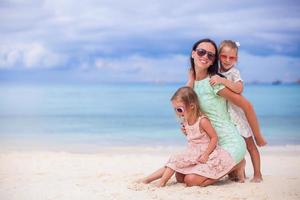 Adorable little girls and young mother on tropical white beach photo