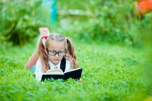 adorable colegiala con libro al aire libre. De vuelta a la escuela foto