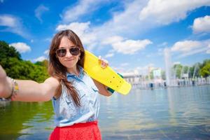 Young girl having fun with skateboard in the park. Lifestyle portrait of young positive woman having fun and enjoy warm weather. photo