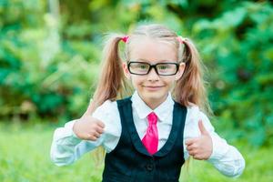 Little happy girl showing thumbs up. Back to school outdoor photo