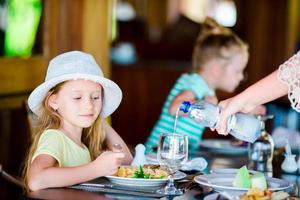 Adorable little girl having breakfast at outdoor cafe photo