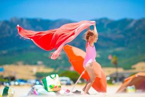 la niña se divierte con una toalla de playa durante las vacaciones tropicales foto