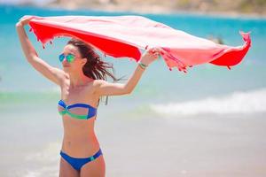 mujer joven con toalla de playa durante las vacaciones tropicales. hermosa chica disfruta de sus vacaciones de verano. foto
