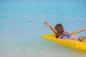 Adorable little girl on air inflatable mattress in the sea photo