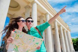 jóvenes amigos turistas que viajan de vacaciones en europa sonriendo felices. familia caucásica con mapa de la ciudad en busca de atracciones foto