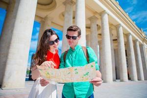 jóvenes amigos turistas que viajan de vacaciones en europa sonriendo felices. familia caucásica con mapa de la ciudad en busca de atracciones foto