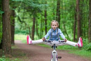 Adorable girl riding a bike at beautiful summer day outdoors photo