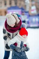 Little adorable girl with her mother skating on ice-rink photo