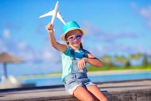 Little adorable girl with big pink suitcase and map of island on white beach photo