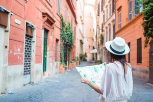 mujer joven feliz con un mapa de la ciudad en la calle del desierto en europa. viaje mujer turista con mapa en roma al aire libre durante las vacaciones en italia. foto