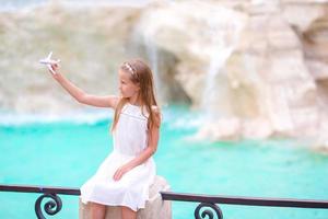 Adorable little girl with toy airplane background Trevi Fountain, Rome, Italy. photo