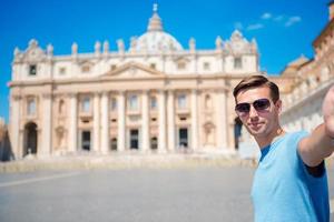 Young man taking selfie background St. Peter's Basilica church in Vatican city, Rome. Caucasian tourist making selfie photo picture on european vacation in Italy.