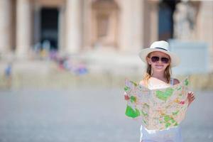 Adorable little girl with touristic map in St. Peter's Basilica square, Italy. Happy toodler kid enjoy italian vacation holiday in Europe. photo