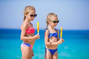 Happy little girls eating ice-cream during beach vacation. People, children, friends and friendship concept photo