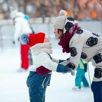 adorable niña patinando en la pista de hielo con su madre foto