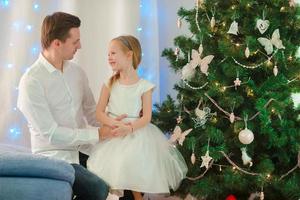 Father with little cute girl near the Christmas tree on xmas eve photo