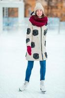 Happy young girl skating on ice rink outdoors photo