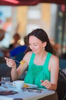 Young woman eating spaghetti at outdoor cafe on italian vacation photo