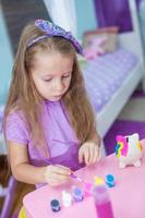 Adorable little girl draws paint in the room photo