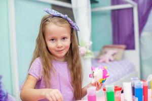 Cute Little girl draws paints at her table in the room photo
