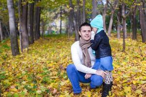 joven padre y su linda hijita susurrando en el parque de otoño foto