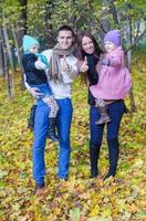 Family of four enjoying autumn vacation and showing a thumbs up photo