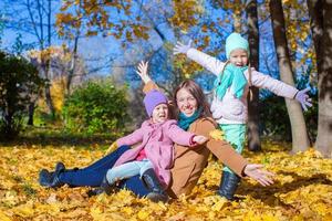 las niñas y la madre joven en el parque de otoño se divierten foto