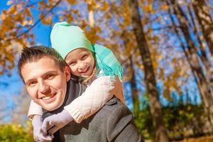 retrato de padre feliz caminando con su linda hija en el parque de otoño foto