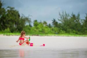 Adorable little girl playing with toys on the beach photo