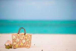 Closeup beautiful bag with frangipani flowers and coconut on white beach photo