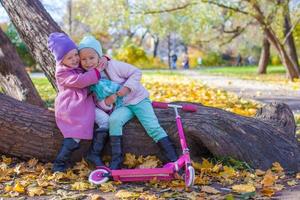 Little beautiful girl with scooter in the autumn park photo
