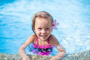 niña linda con flor detrás de la oreja en la piscina foto
