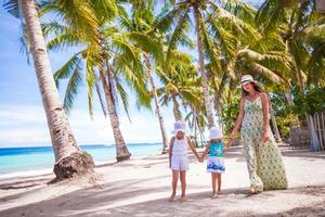 Mother walking with her two kids along a tropical beach photo