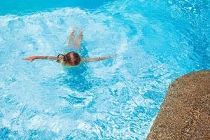 Little cute girl swims in the swimming pool at exotic resort photo