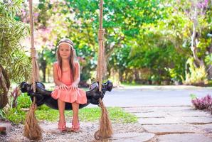 Beautiful girl swinging on a swing in cozy lovely flowered courtyard photo