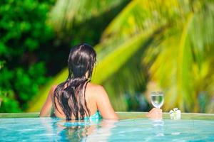 vista trasera de una joven hermosa mujer disfrutando de la lujosa y tranquila piscina foto