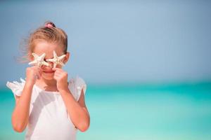 Adorable little girl with starfish on the beach photo