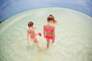 Adorable little girls have fun on the beach photo