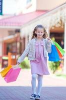 adorable niña caminando con bolsas de compras al aire libre foto