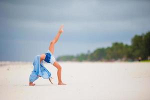 Adorable active little girl at beach during summer vacation photo