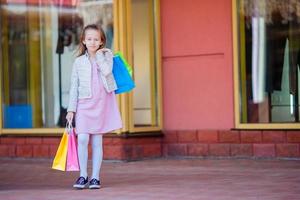 Adorable little girl shopping in the city outdoors photo