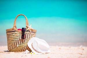 Beach accessories - straw bag, sunglasses, hat on the beach photo