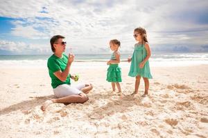 el joven padre y sus adorables hijas se divierten en la playa caribeña foto