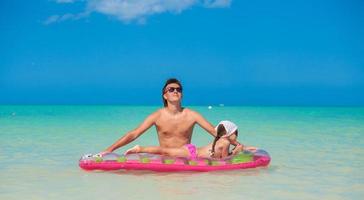 Little girl with young father on an air mattress in the sea photo