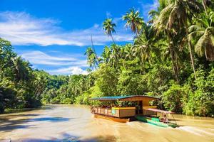 barco de crucero exótico con turistas en un río de la selva loboc, bohol foto