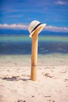 Straw hat at wooden fence on the white sandy beach with an ocean view photo