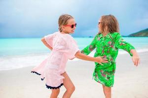 Two little happy girls have a lot of fun at tropical beach playing together photo