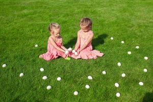 Adorable little girls having fun with Easter Eggs on green grass photo